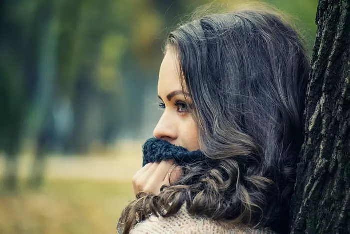 Vacker kvinna som lutar sig mot ett träd