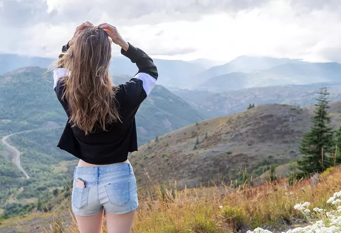 Ung kvinna på toppen av ett berg